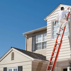House painter painting house exterior with paint brush