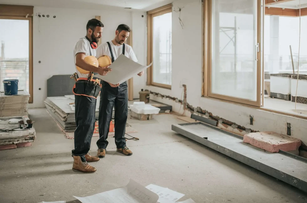 Construction workers analyzing blueprints in the apartment.