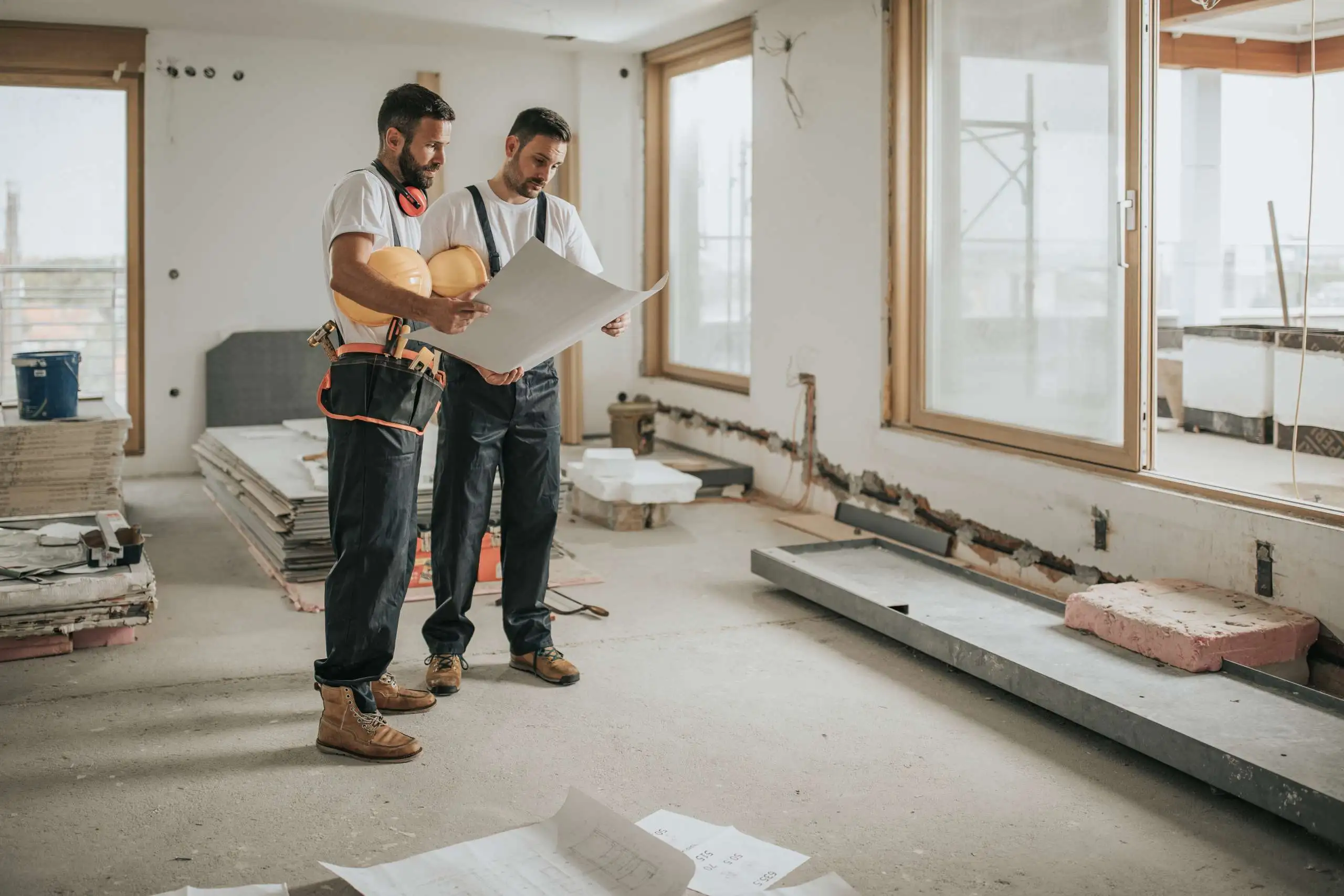 Construction workers analyzing blueprints in the apartment.