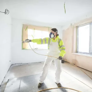 Painter paints a wall using spray gun