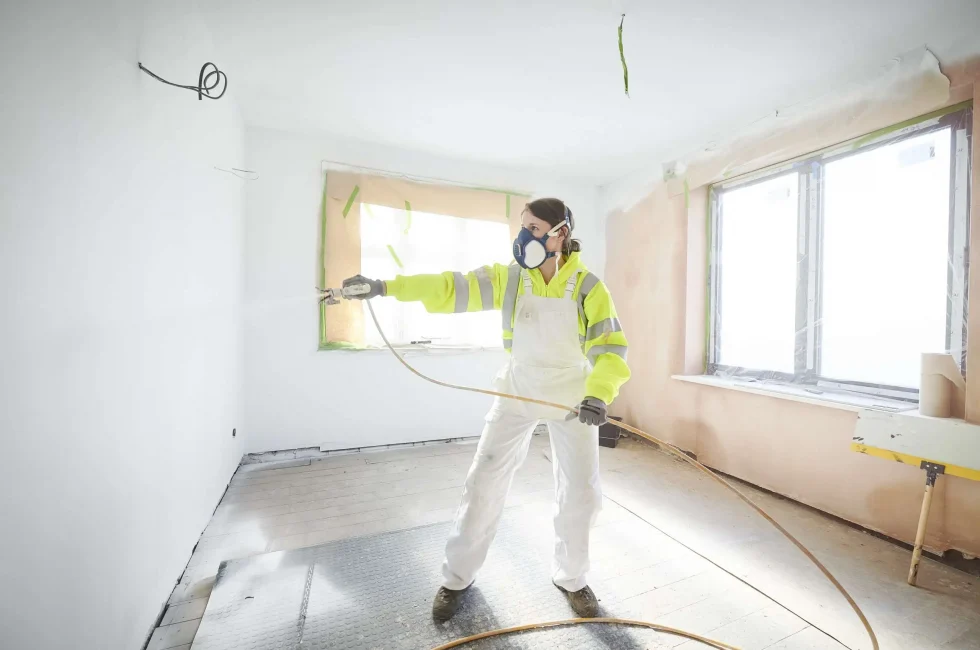 Painter paints a wall using spray gun