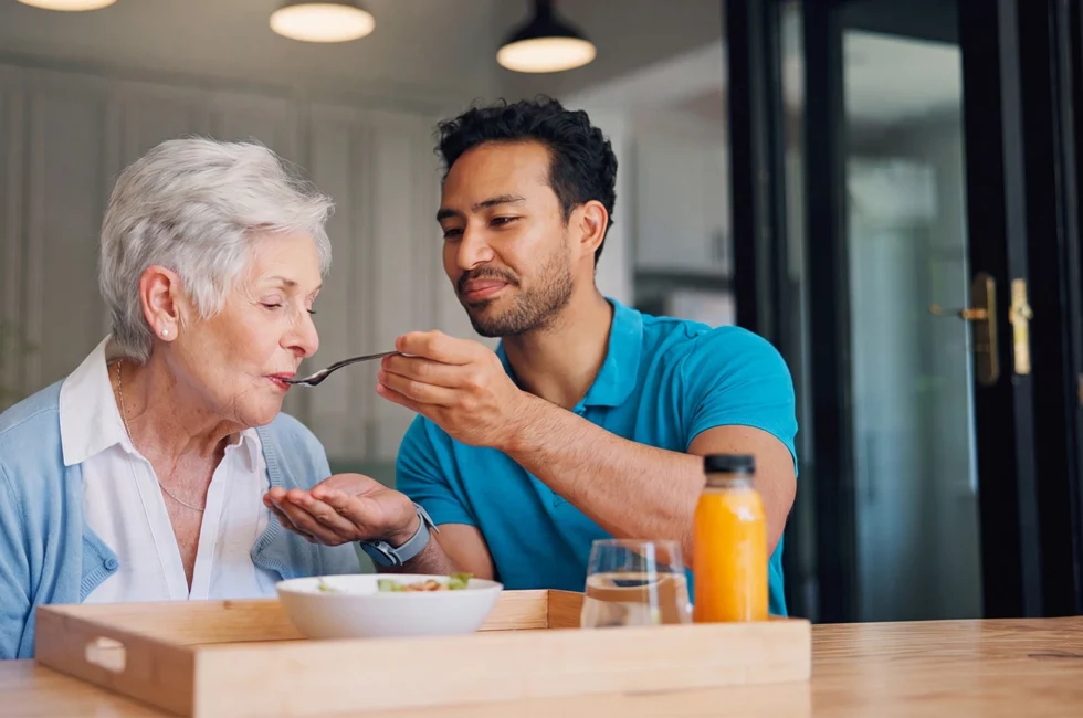 Home carer helping feed a female senior citizen 