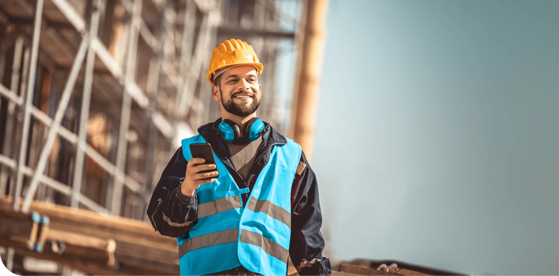 Carpenter on site with a mobile device in his hand and wearing a hard hat