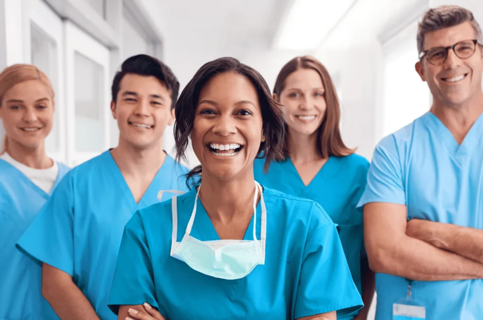 A group of happy male and female nurses smiling at the camera at their place of work
