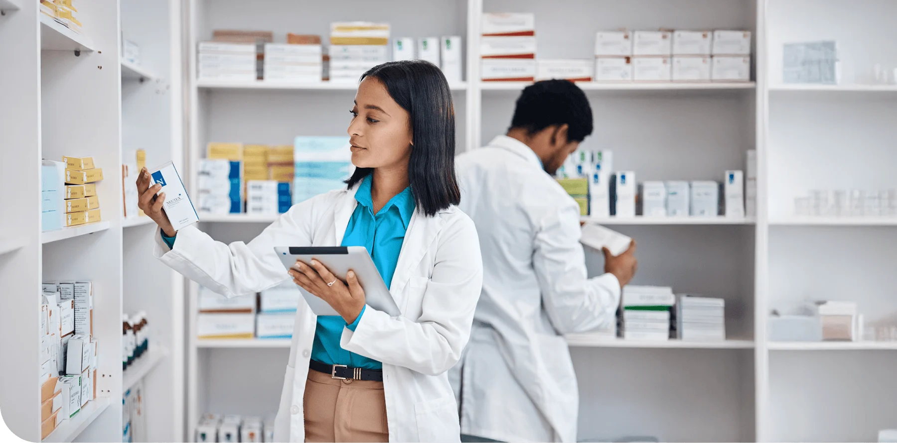 Pharmacist at the pharmacy reviewing medication and using a tablet with a colleague. 